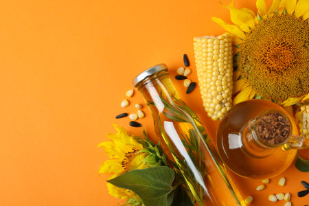Bottle and jug of oil and ingredients on orange backgroundの写真素材