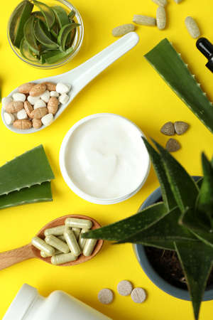 Concept of herb pills and cosmetics with aloe on yellow backgroundの写真素材