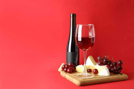Board with wine, cheese and grape on red backgroundの写真素材
