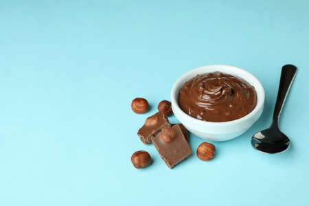 Bowl with chocolate paste, nuts, chocolate and spoon on blue backgroundの写真素材