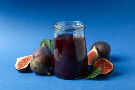 Jars with fig jam and ingredients on blue backgroundの写真素材