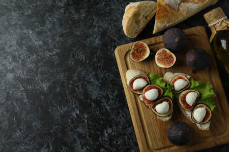 Concept of tasty food with bruschetta with fig on black smokey tableの写真素材