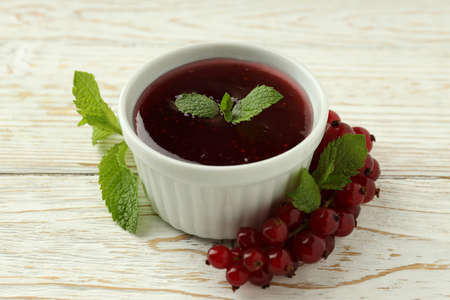Bowl of cranberry sauce on white wooden background
