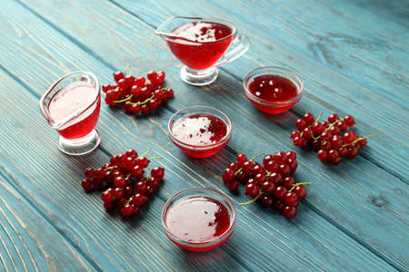 Bowls with cranberry sauce and ingredients on wooden backgroundの写真素材