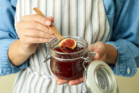 Woman in apron holds jar of fig jam, close upの写真素材