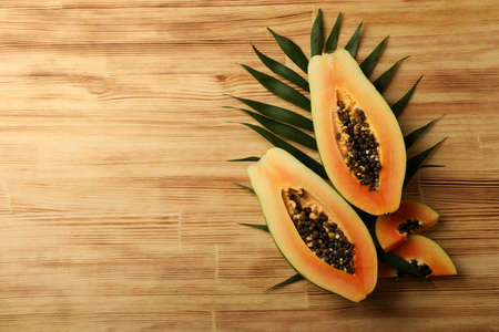 Ripe papaya with leaves on wooden backgroundの写真素材