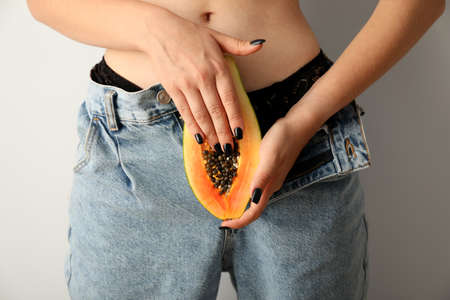 Masturbation concept with woman holding papaya, front viewの写真素材