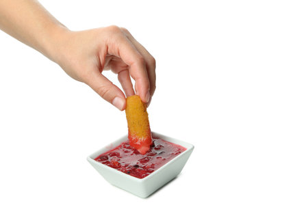 Female hand dips cheese stick in cranberry sauce, isolated on white backgroundの写真素材