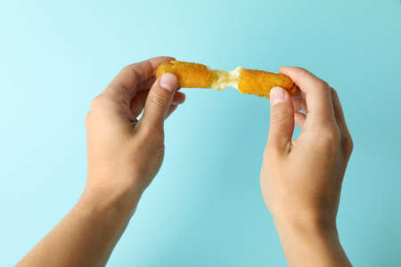 Female hands hold cheese stick on blue backgroundの写真素材