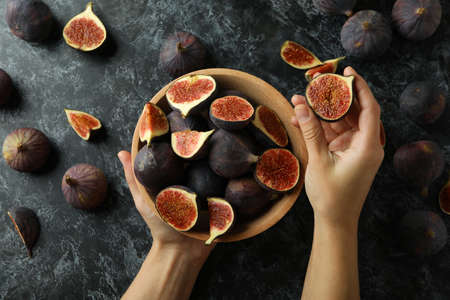 Female hands hold bowl with fig on black smokey backgroundの写真素材