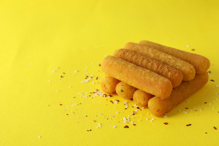Cheese sticks and spices on yellow backgroundの写真素材