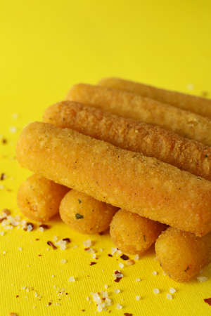 Cheese sticks and spices on yellow backgroundの写真素材