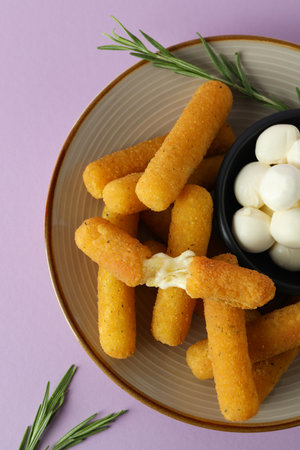 Plate with cheese sticks, mozzarella and rosemary on violet backgroundの写真素材