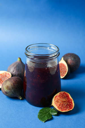Jars with fig jam and ingredients on blue backgroundの写真素材