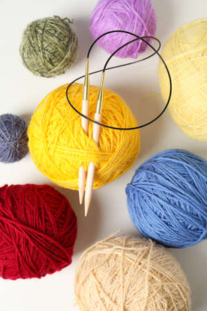 Balls of yarn with knitting needles on white background