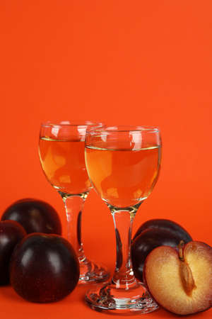 Plum vodka shots and ingredients on orange backgroundの写真素材