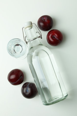 Bottle and shot of plum vodka and ingredients on white backgroundの写真素材