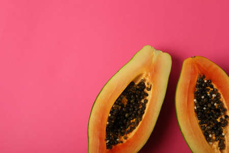 Halves of ripe papaya on pink background