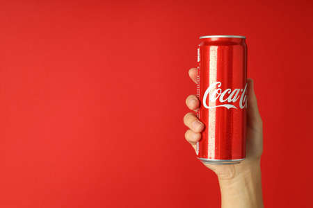 Odessa, Ukraine - September 23, 2021: Female hand holds Coca - Cola can on red backgroundのeditorial素材