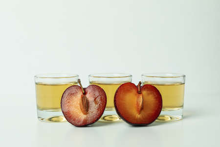 Plum vodka shots and ingredients on white background