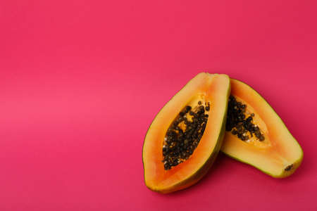 Halves of ripe papaya on pink background