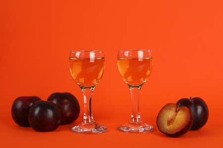 Plum vodka shots and ingredients on orange backgroundの写真素材