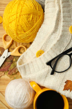 Concept of knitting with yarn balls on wooden table, top view.