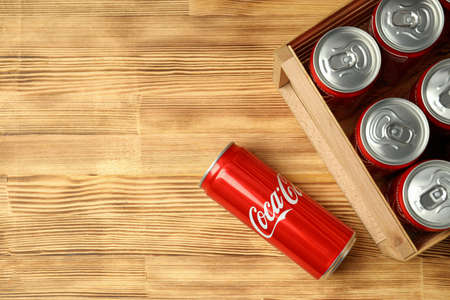 Odessa, Ukraine - September 23, 2021: Coca - cola can and box with cans on wooden table.のeditorial素材