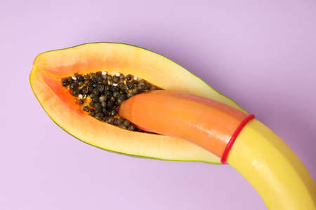 Papaya and banana with condom on violet backgroundの写真素材