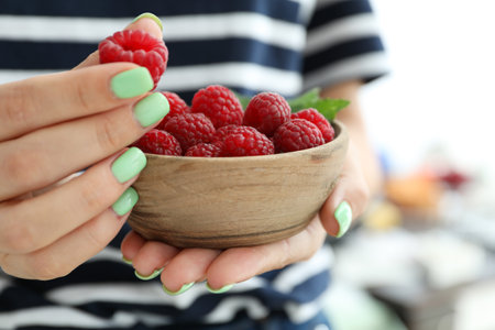 Woman holding wooden bowl with raspberries, cloce up.の写真素材