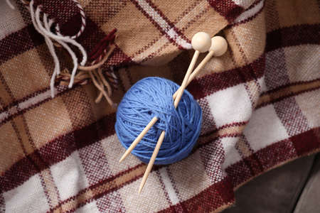 Ball of yarn with knitting needles on checkered plaidの写真素材