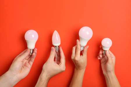 Hands hold energy saving bulbs on red background.の写真素材