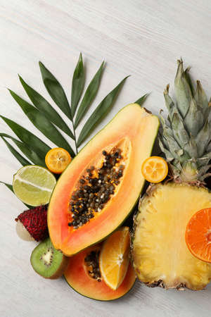 Ripe exotic fruits on white wooden background.