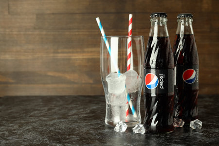 Odessa, Ukraine - September 23, 2021: Pepsi bottles, glass with straws and ice against wooden background.のeditorial素材
