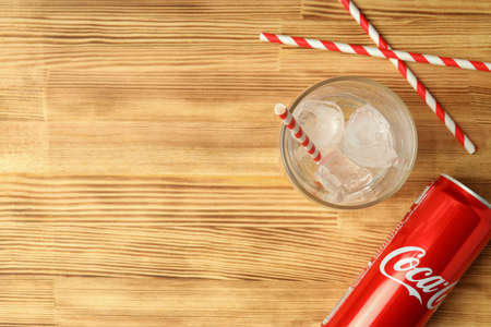 Odessa, Ukraine - September 23, 2021: Coca - cola can and glass with ice, and straws on wooden table.のeditorial素材