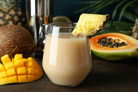 Pina colada cocktail and ingredients on wooden table.