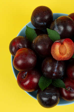 Blue bowl with plums on yellow background.の写真素材