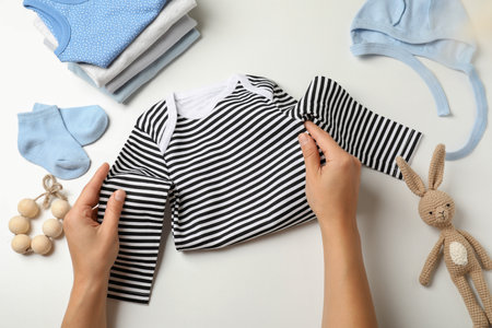 Female hands fold baby clothes on white background.の写真素材
