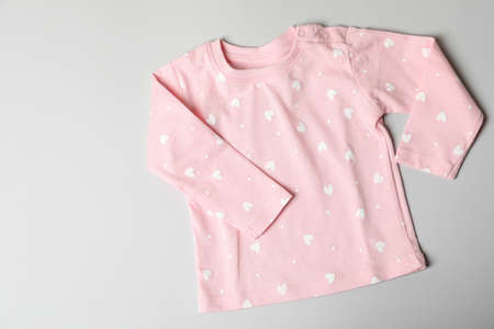Pink female baby clothes on light gray background.