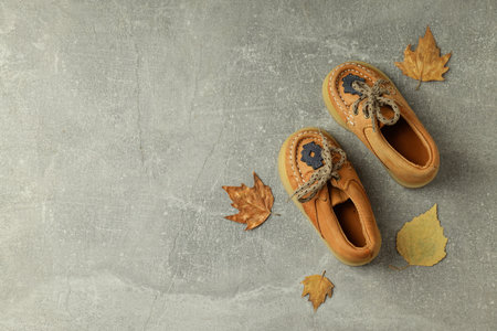 Baby shoes and leaves on gray textured background.の写真素材