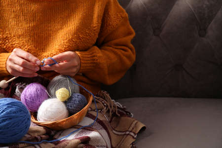 Girl in a sweater knits sitting on the sofa, space for textの写真素材