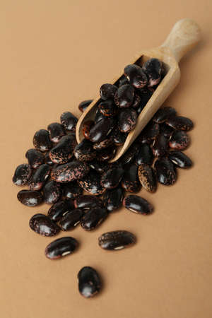 Scoop with black beans on beige background