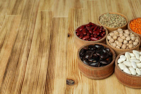 Bowls with different types of beans on a wooden background.の写真素材