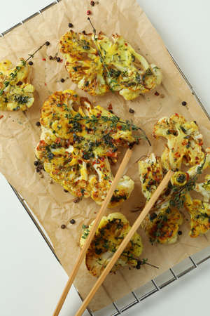 Baking rack with baked cauliflower and wooden tongs on white background.の写真素材