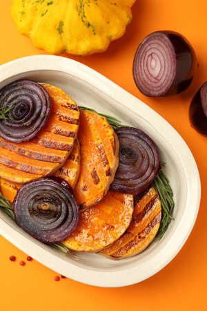 Baking tray with baked pumpkin on orange background.の写真素材