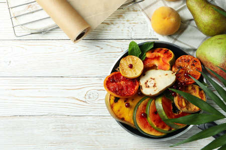 Concept of tasty food with grilled fruits on white wooden table.の写真素材