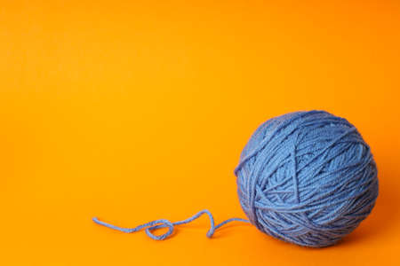 Blue ball of yarn on orange background.