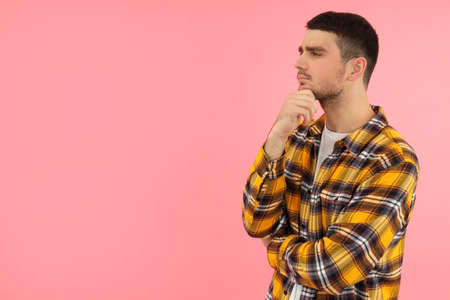 Pensive young man on pink background, space for text.