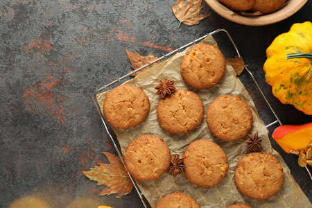 Concept of tasty food with pumpkin cookies on dark textured background.