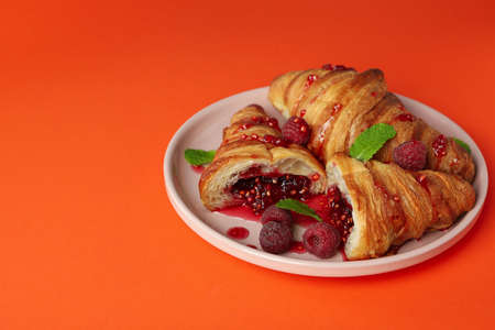 Plate with croissants with raspberry jam on orange backgroundの写真素材